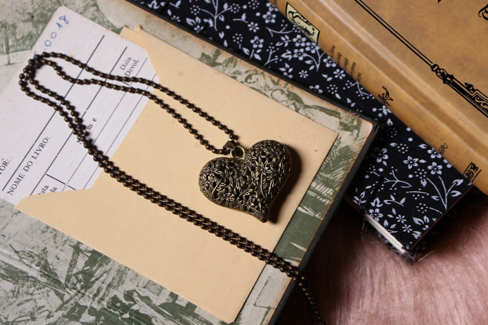 a book and a heart shaped pendant on a table
