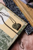 Close-up of a delicate red heart pendant resting on an open book page, symbolizing love and stories intertwined.