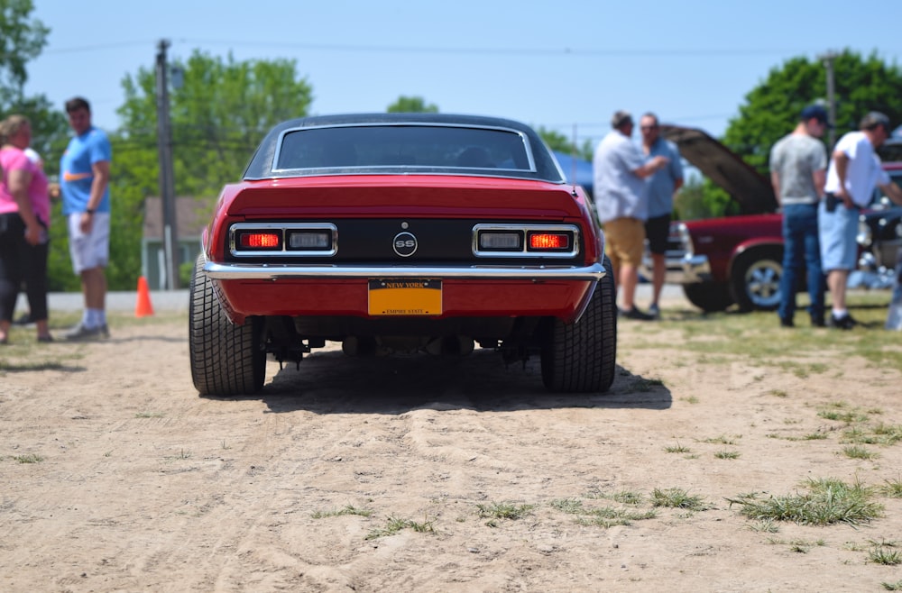 a red car parked on top of a dirt road