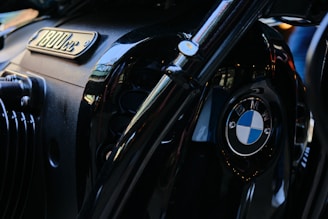 A close-up view of a BMW motorcycle engine. The image prominently features the BMW logo and an emblem indicating an 1800cc engine capacity. The surface has a shiny, metallic black finish with reflective accents.