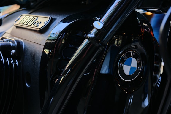 A close-up view of a BMW motorcycle engine. The image prominently features the BMW logo and an emblem indicating an 1800cc engine capacity. The surface has a shiny, metallic black finish with reflective accents.