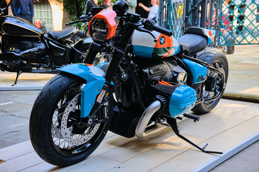 a blue and orange motorcycle parked on a wooden platform