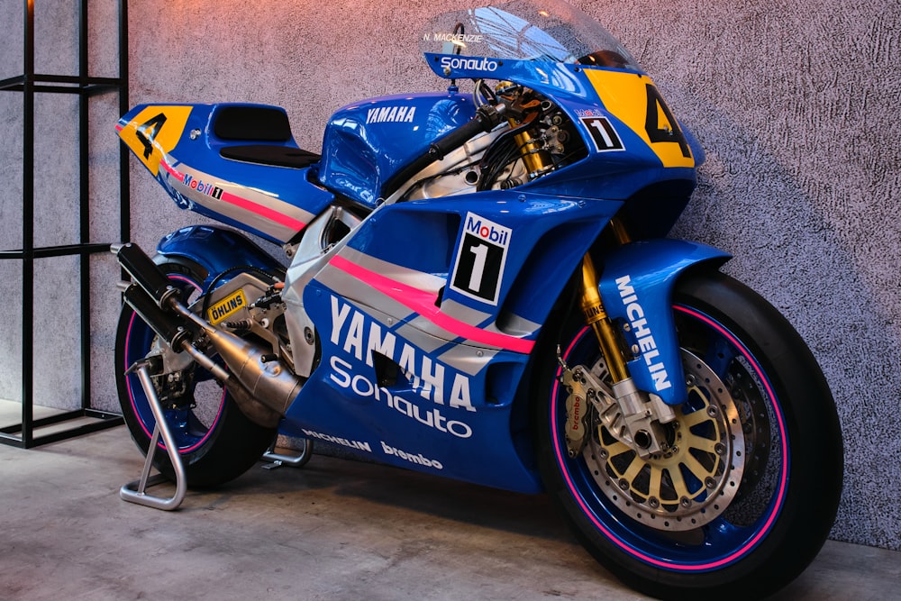 a blue and yellow motorcycle parked next to a wall