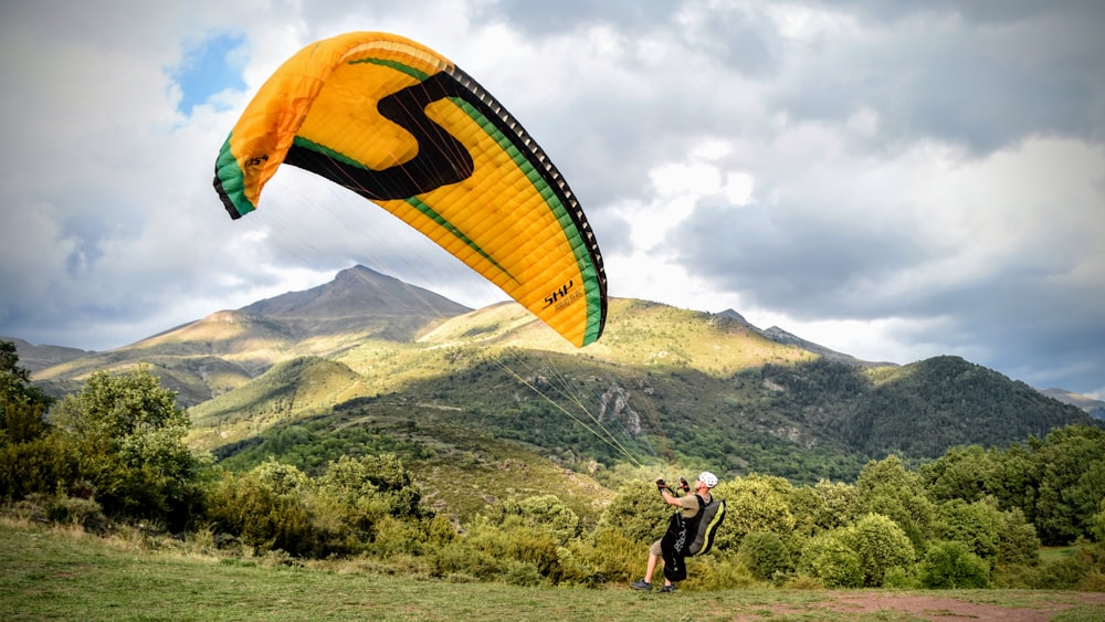 a man is flying a large kite in the mountains