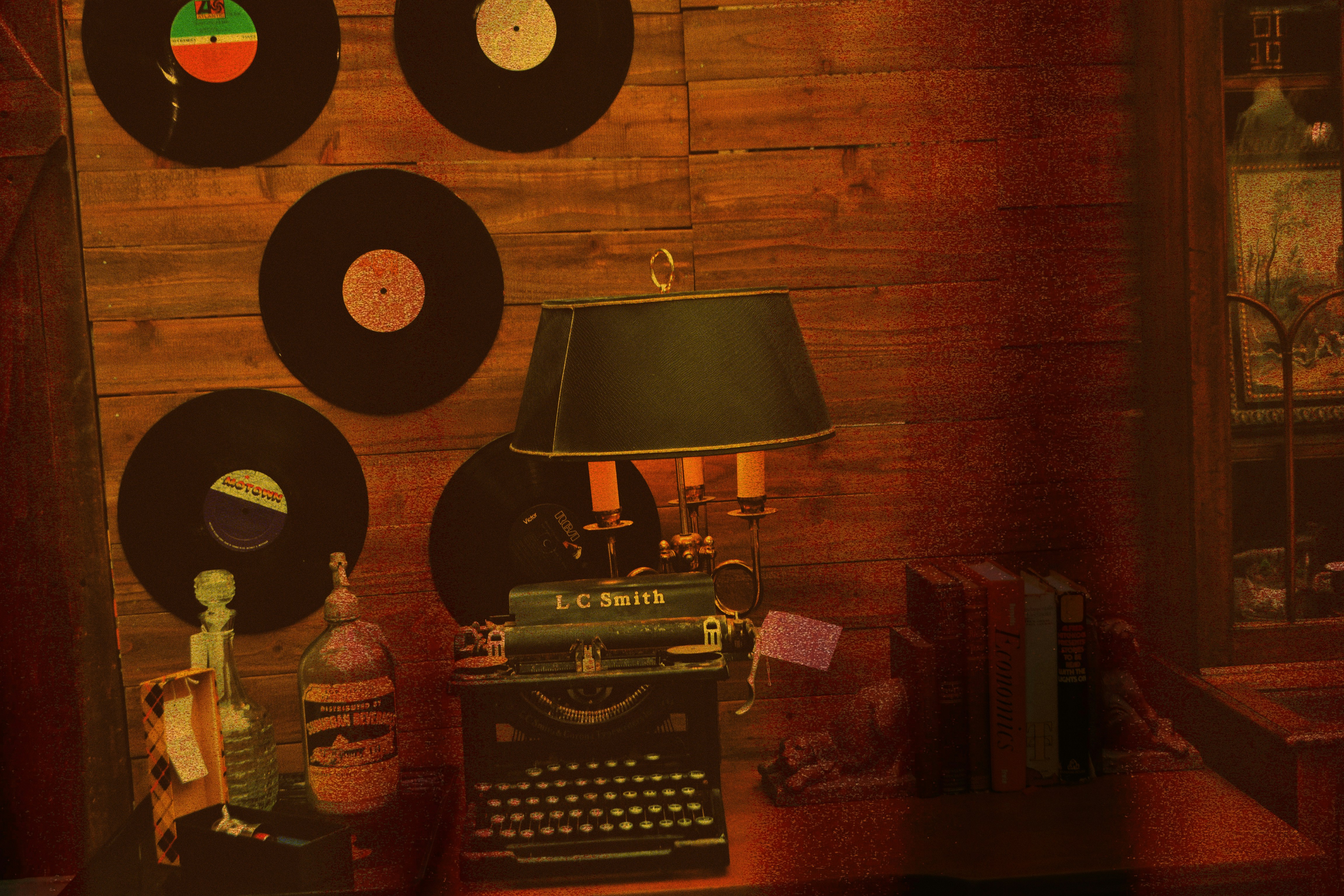 a room with a typewriter, lamp, and several records on the wall