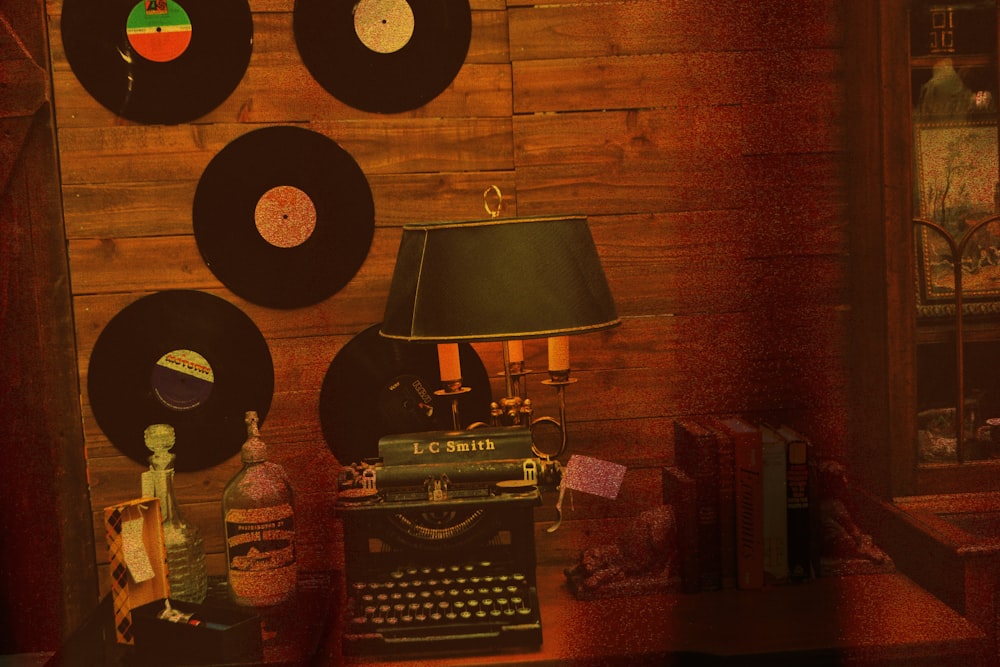 a room with a typewriter, lamp, and several records on the wall