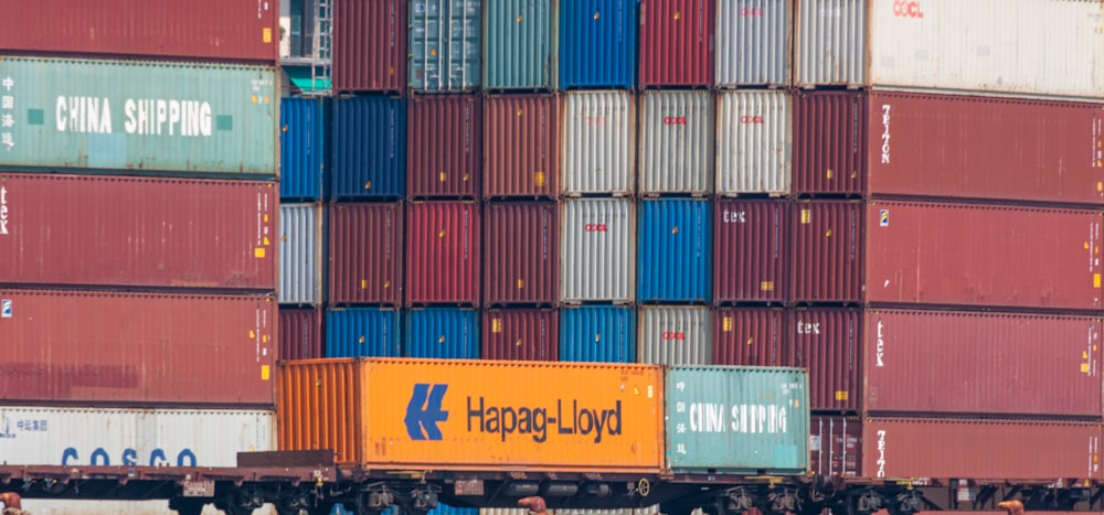 a large cargo truck is parked in front of a large stack of shipping containers