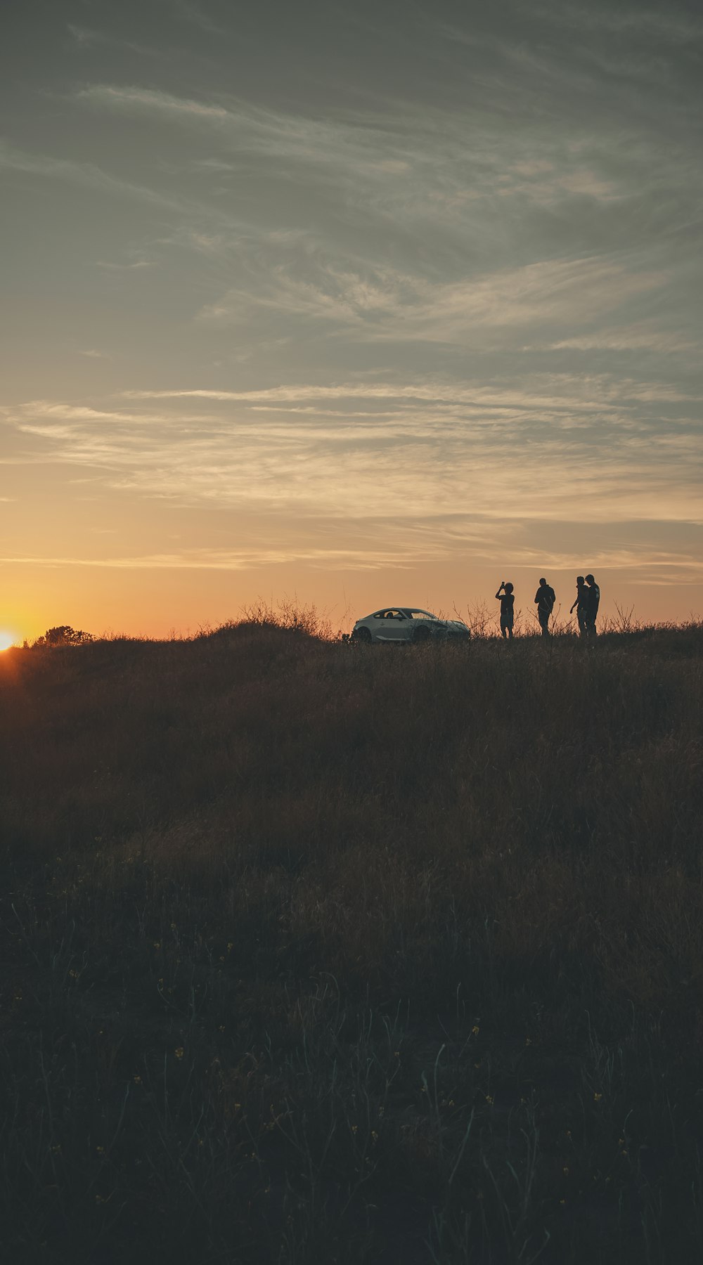 a group of people standing on top of a grass covered hillside