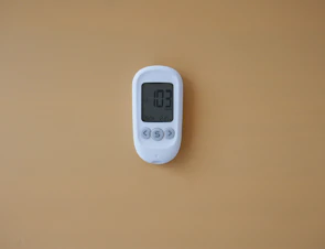 a digital thermometer on a tan wall