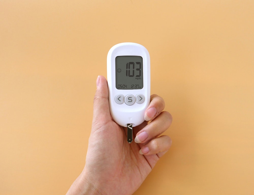 A person holding a digital thermometer in their hand photo – Free Sugar  meter Image on Unsplash
