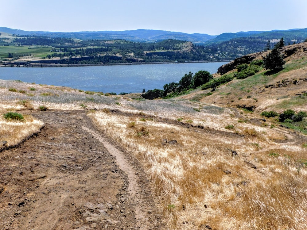 a dirt road going up a hill next to a body of water
