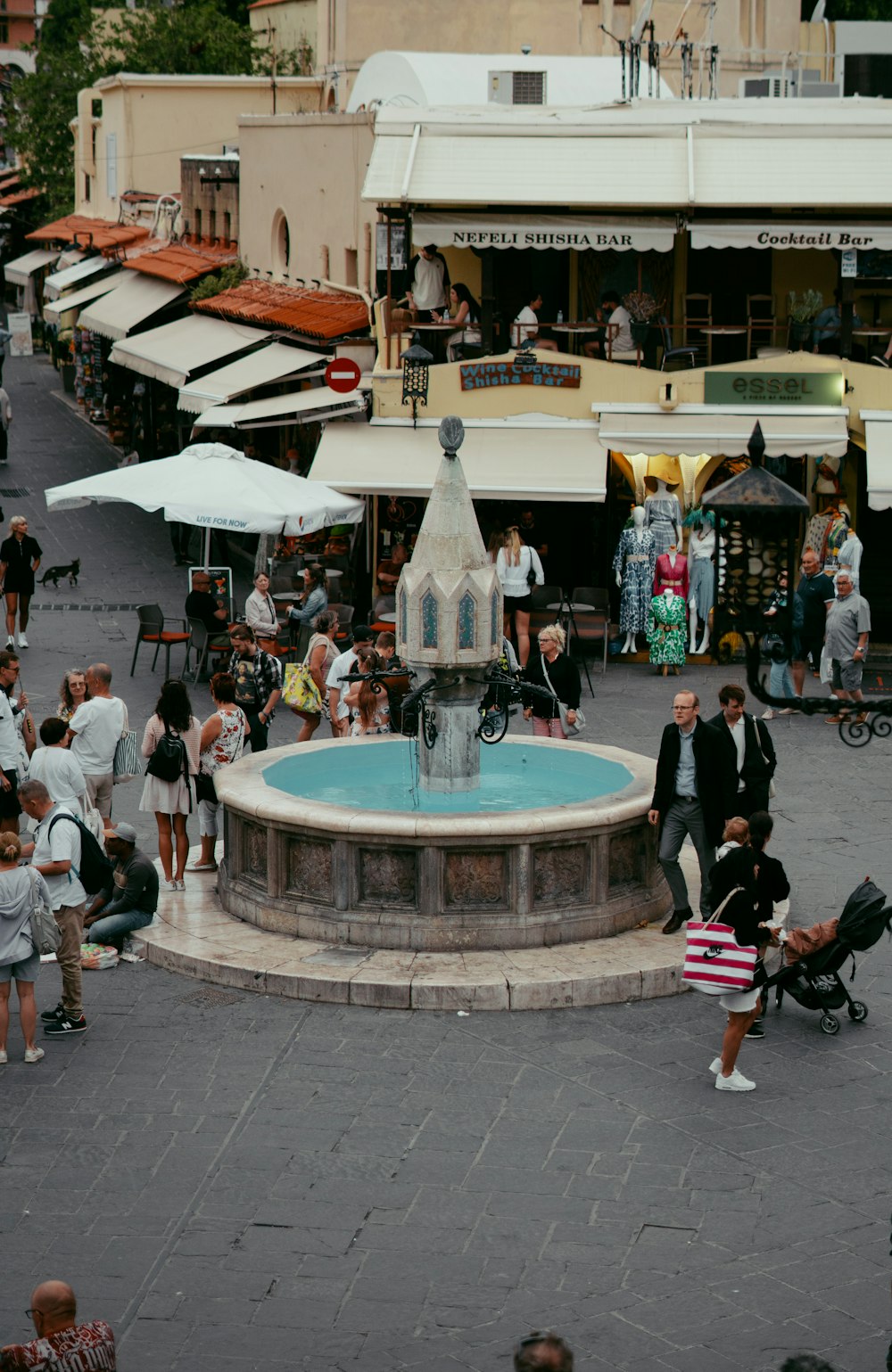 a crowd of people standing around a fountain