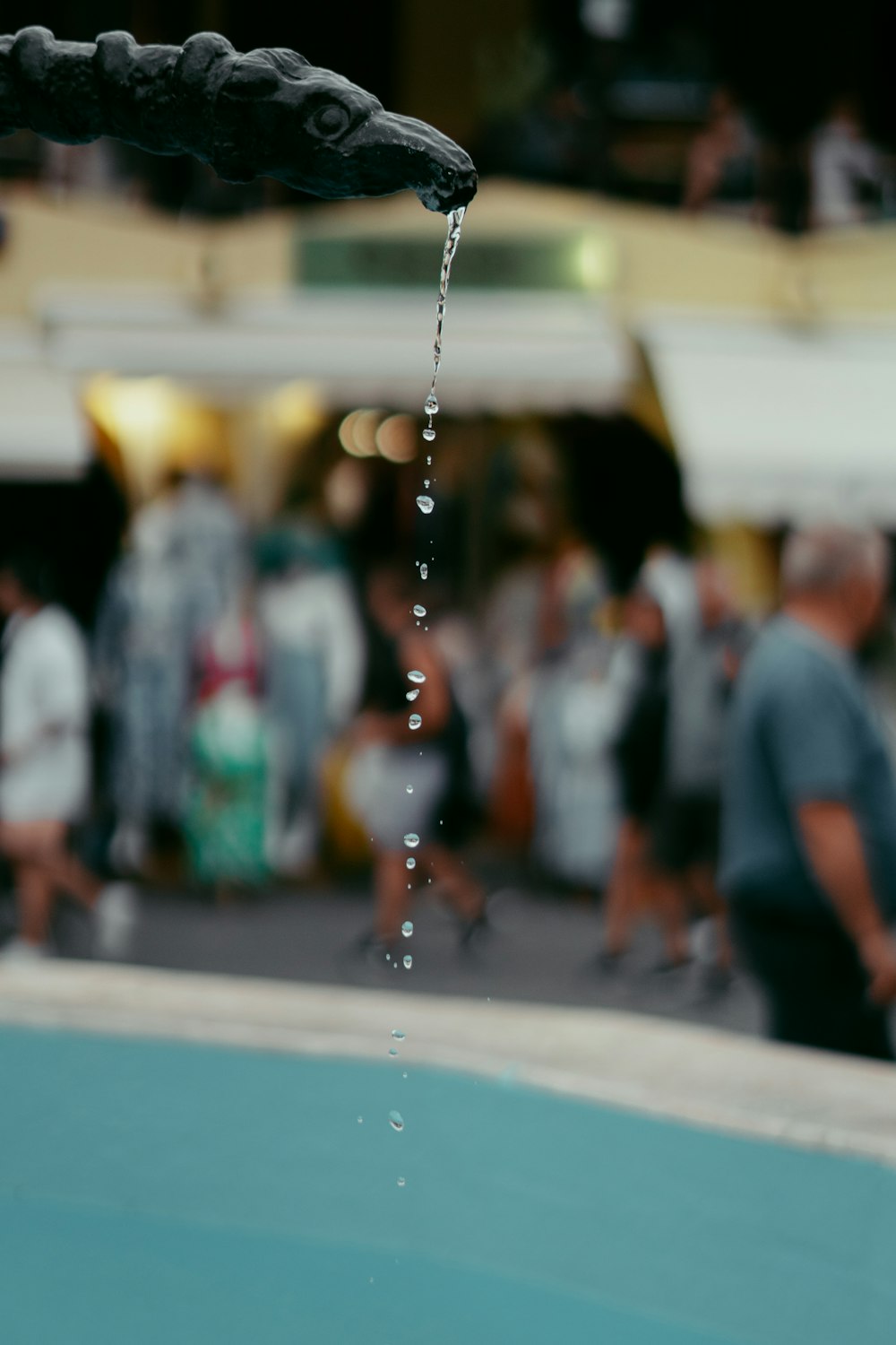 a close up of a water faucet with people in the background