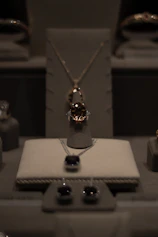 Elegant display of golden and beige jewelry pieces arranged on a soft beige background with subtle golden reflections.