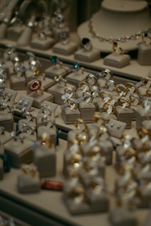 Various pieces of jewelry including rings and earrings are elegantly displayed on cushion mounts. The arrangement showcases the intricate design and sparkle of each item, with gold and silver tones standing out among gemstones of different colors.