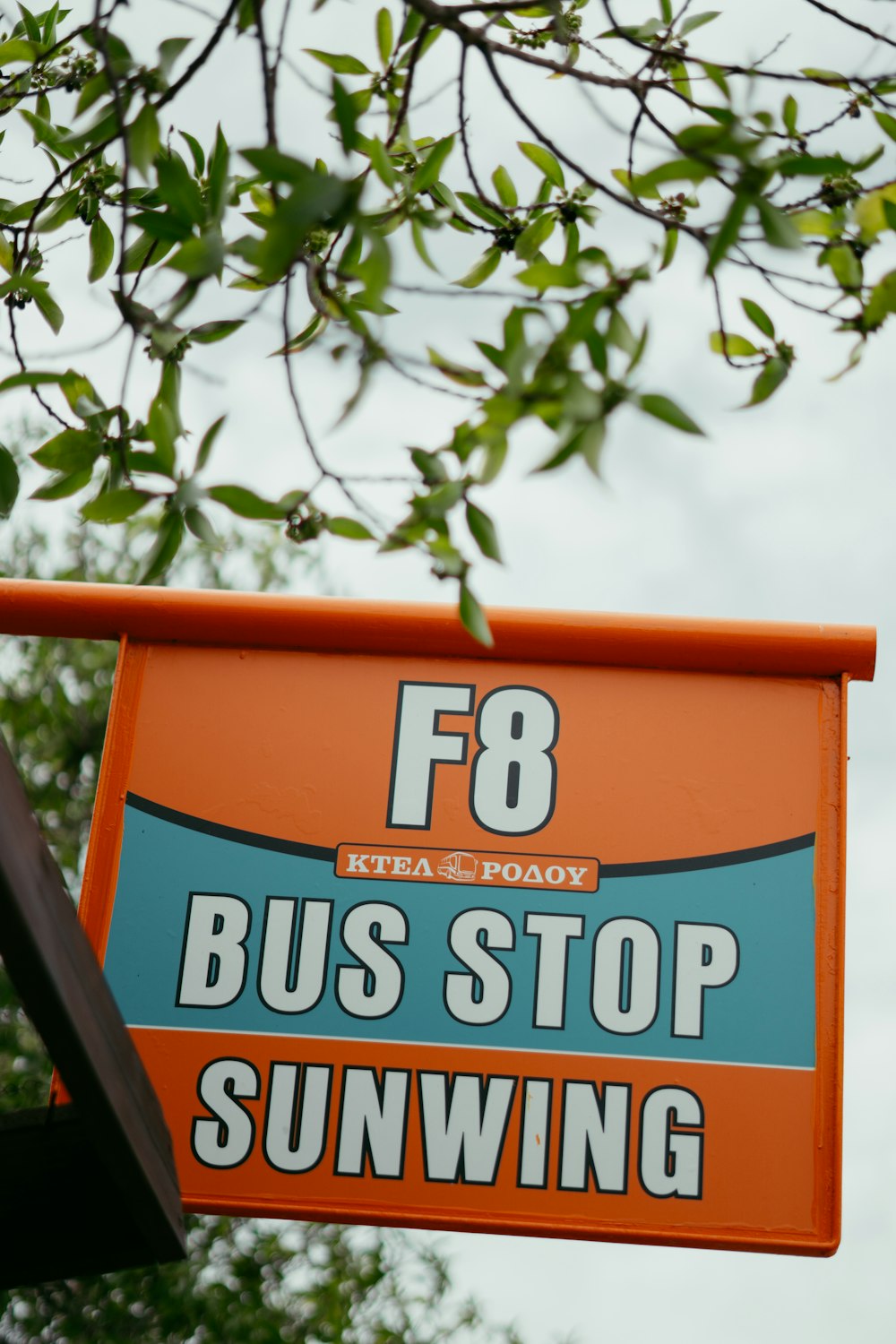 a bus stop sign hanging off the side of a building