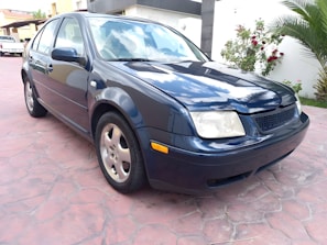 A shiny used sedan parked in a sunny driveway, ready for a new owner