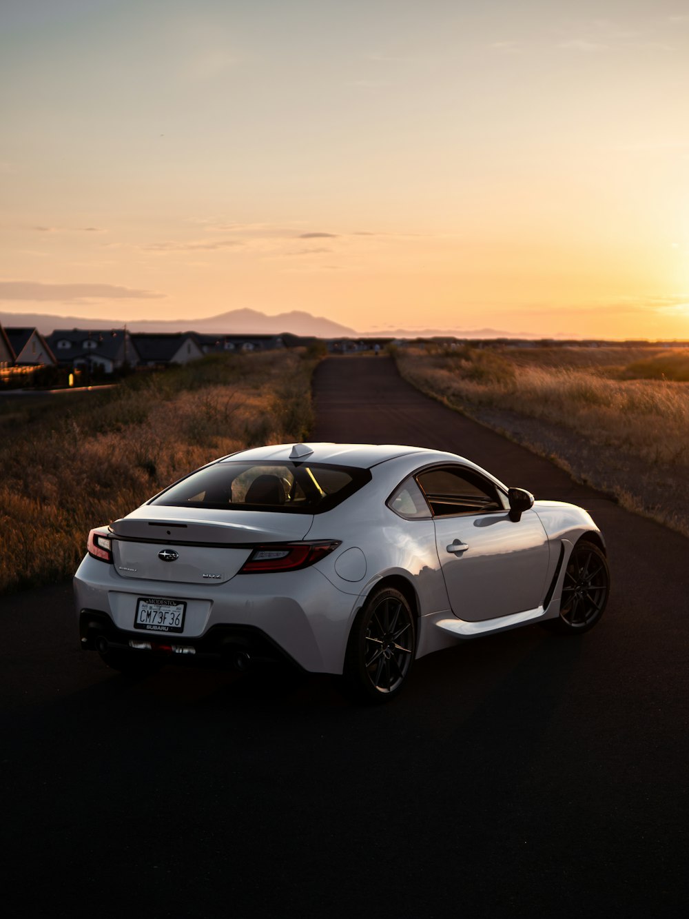 a white sports car driving down a rural road