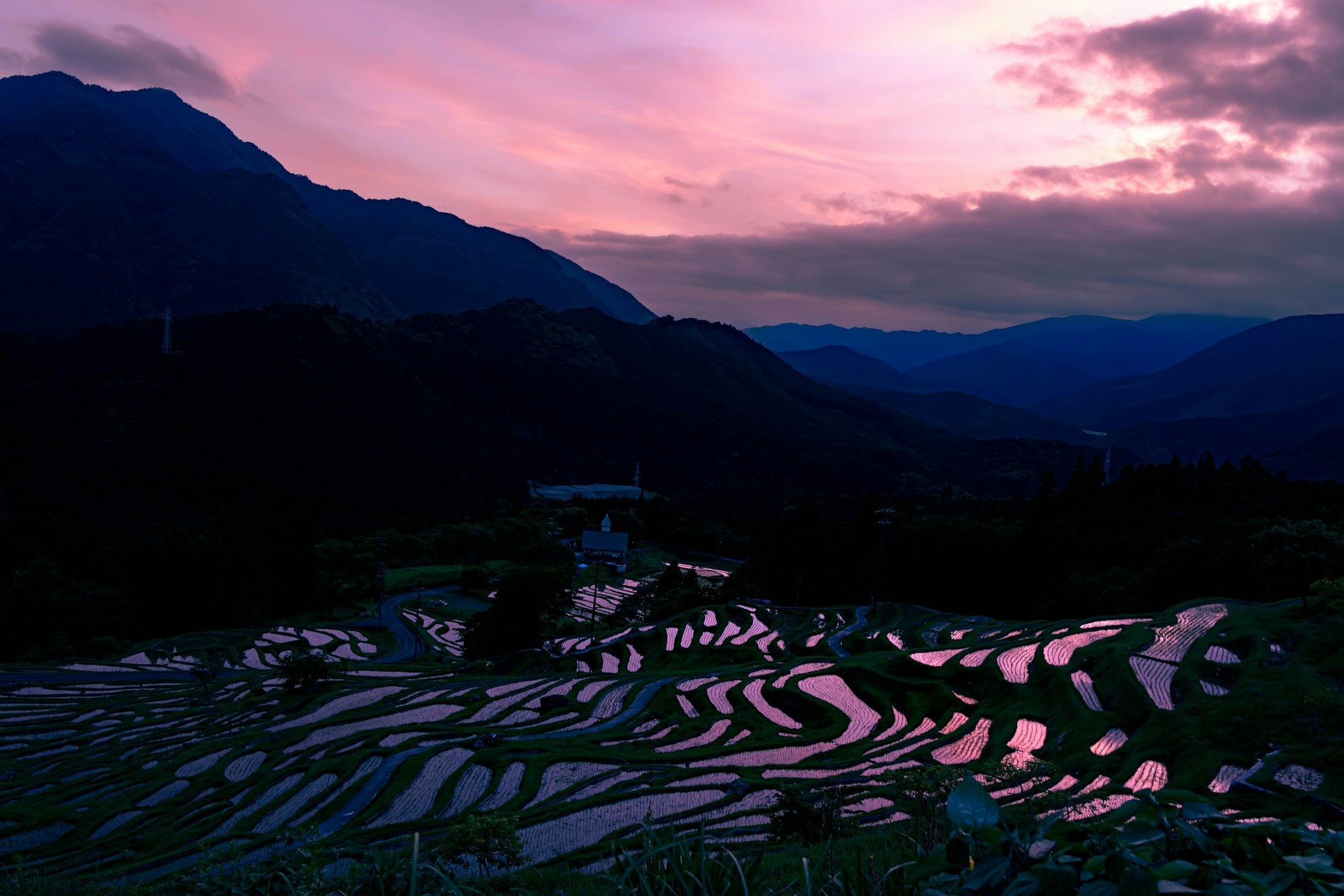 A breathtaking sunset over Bali's lush rice terraces with vibrant orange and pink skies.