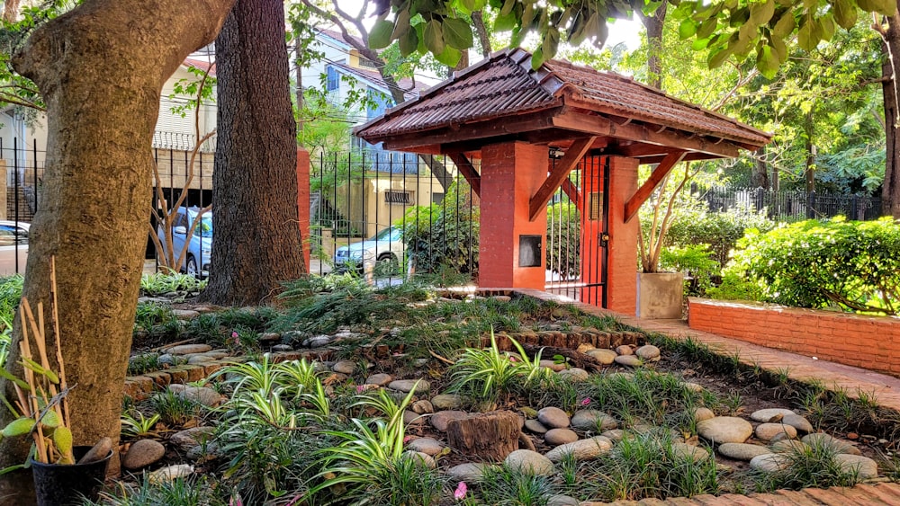 a gazebo in a garden surrounded by trees and plants