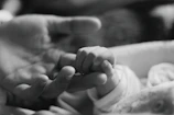 Close-up of delicate baby hand resting on mother's finger, symbolizing connection