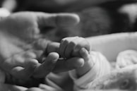 A close-up of a baby's hand holding onto a mother's finger, symbolizing connection.
