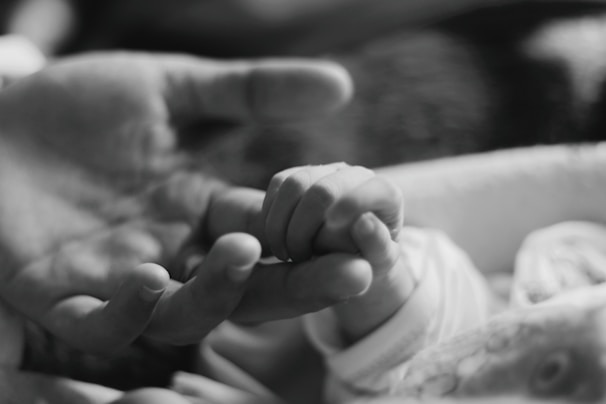 A black-and-white photo of a child holding hands with an elderly parent, symbolizing early responsibility.