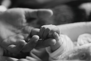 Close-up of tiny baby hands grasping a mother's finger, symbolizing connection and trust.