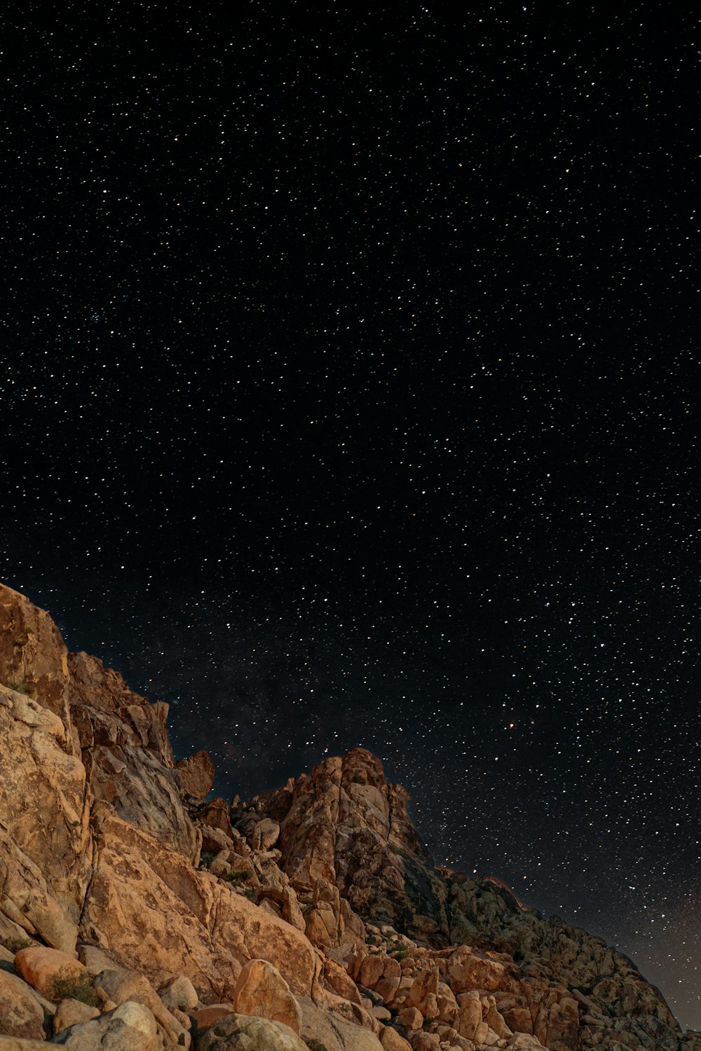 the night sky is full of stars above a rocky mountain