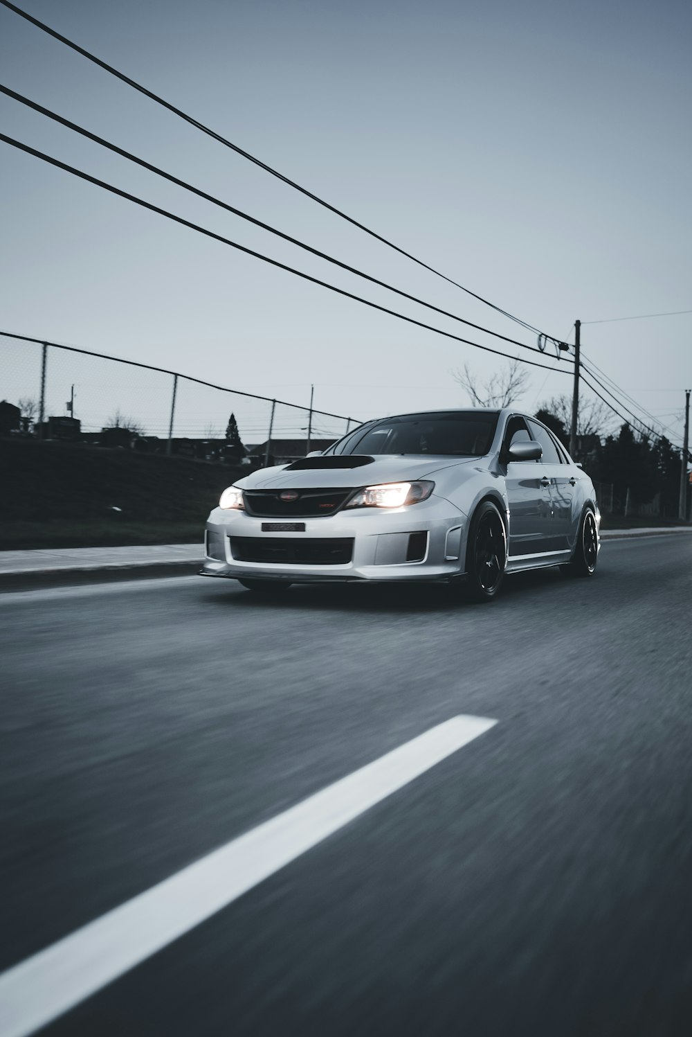 a white car driving down a street next to power lines