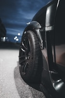 A close-up shot of a car's polished tire and sleek bodywork gleaming under soft evening lights.