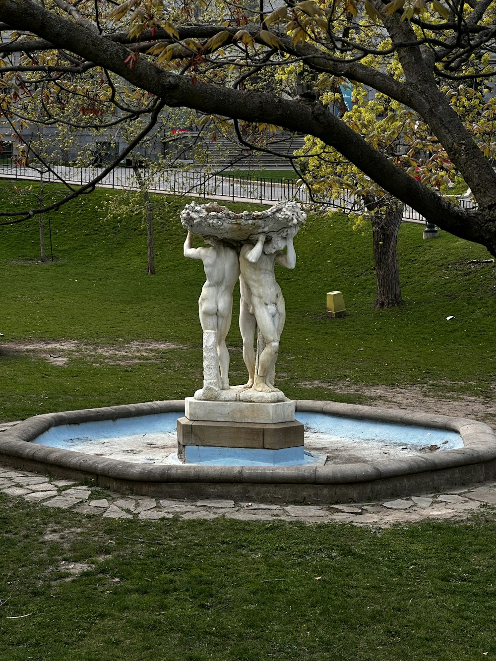 a statue of two men holding a bowl in a park