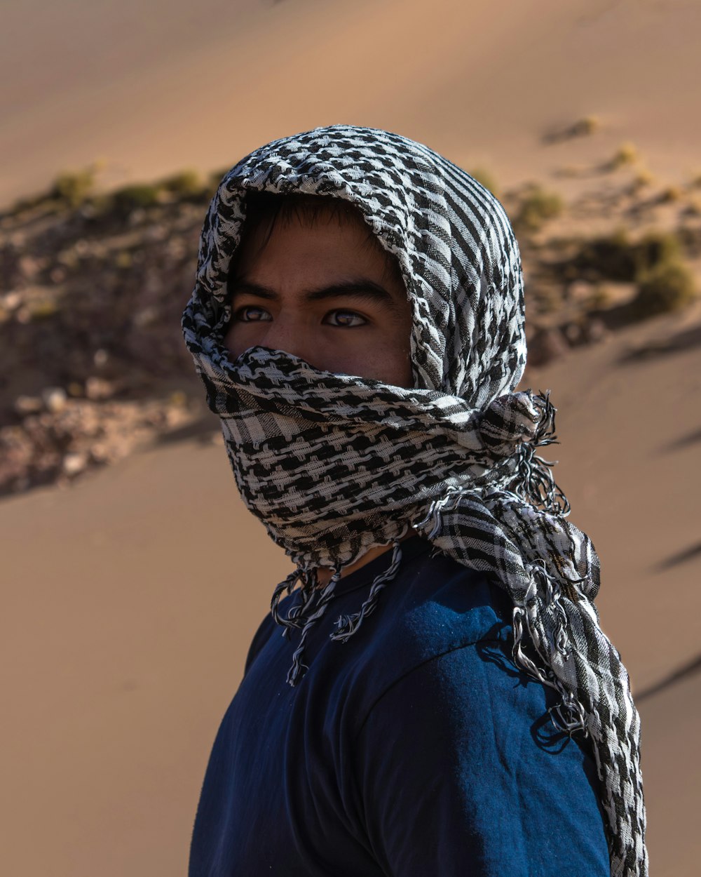 a man with a scarf on his head in the desert