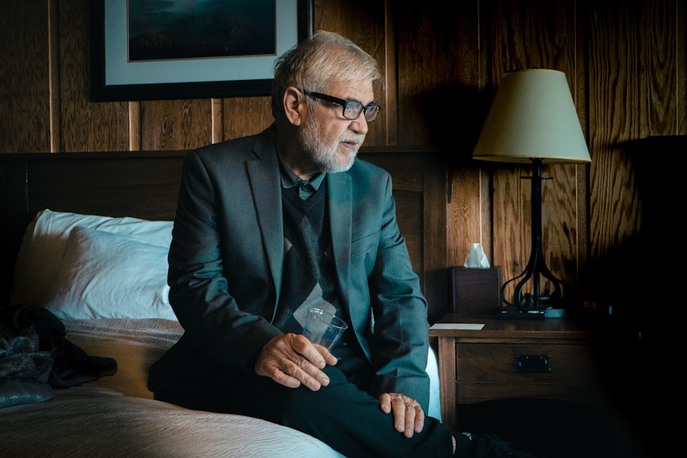 a man in a suit sitting on a bed