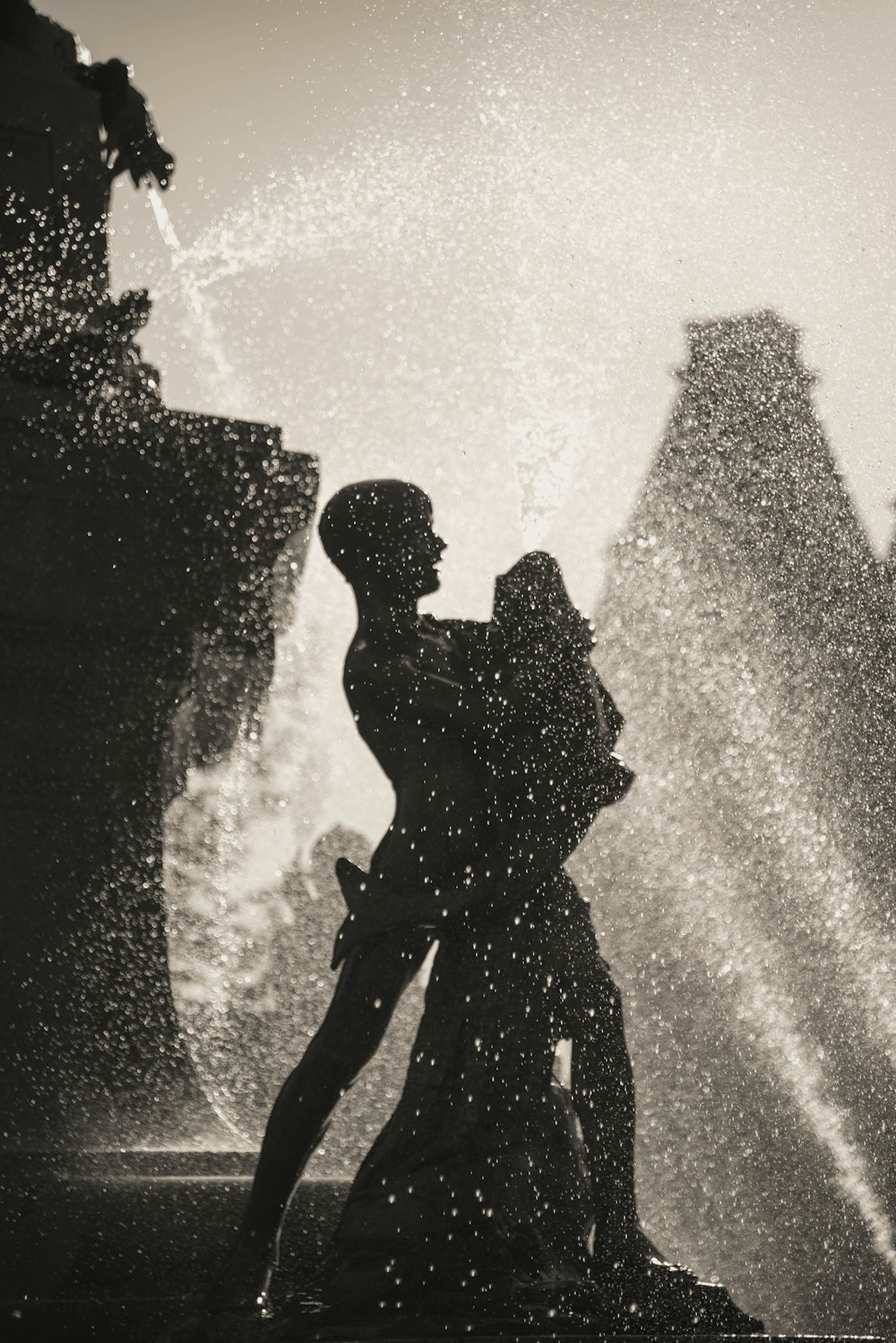 a couple kissing in front of a fountain