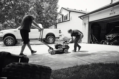 a man pushing a lawn mower next to another man