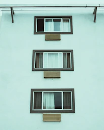 Apartment building facade showing multiple windows fitted with discreet air vents.