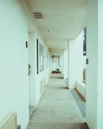 a long hallway leading to a building with a clock on the wall