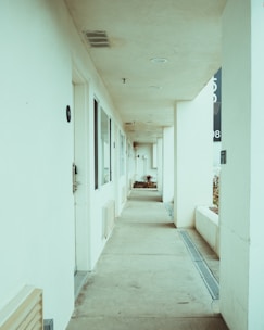 a long hallway leading to a building with a clock on the wall