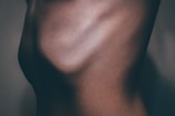 A close-up view of a human torso, highlighting the contours and shadows of the skin. The lighting emphasizes the ribcage and muscular definition.