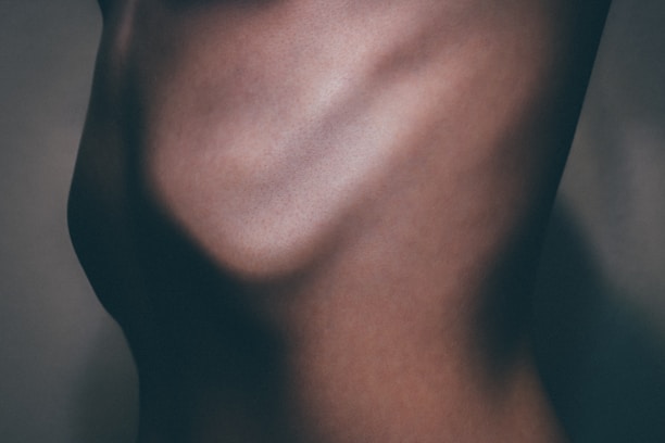 A close-up view of a human torso, highlighting the contours and shadows of the skin. The lighting emphasizes the ribcage and muscular definition.