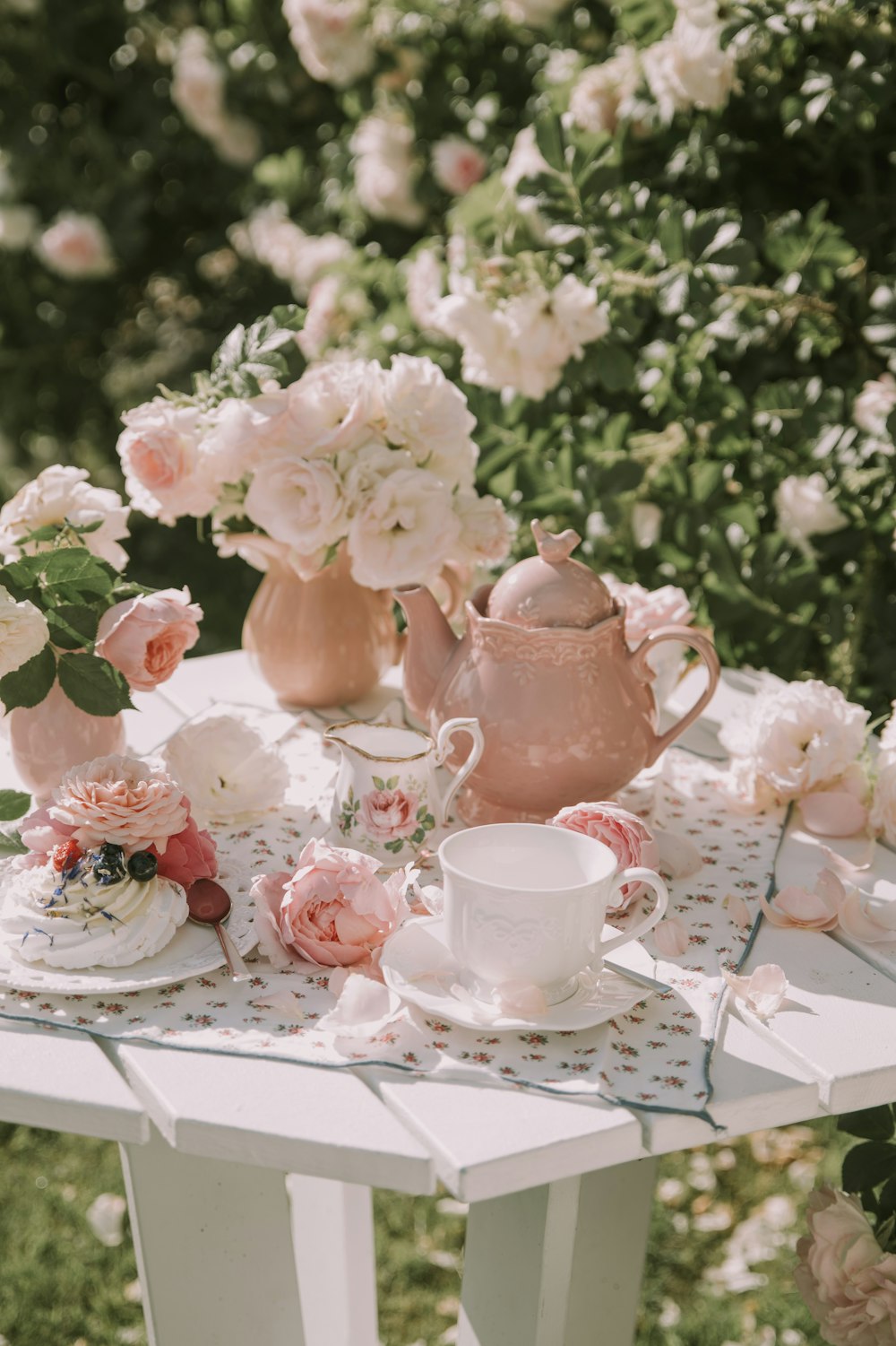 a white table topped with pink flowers and tea cups