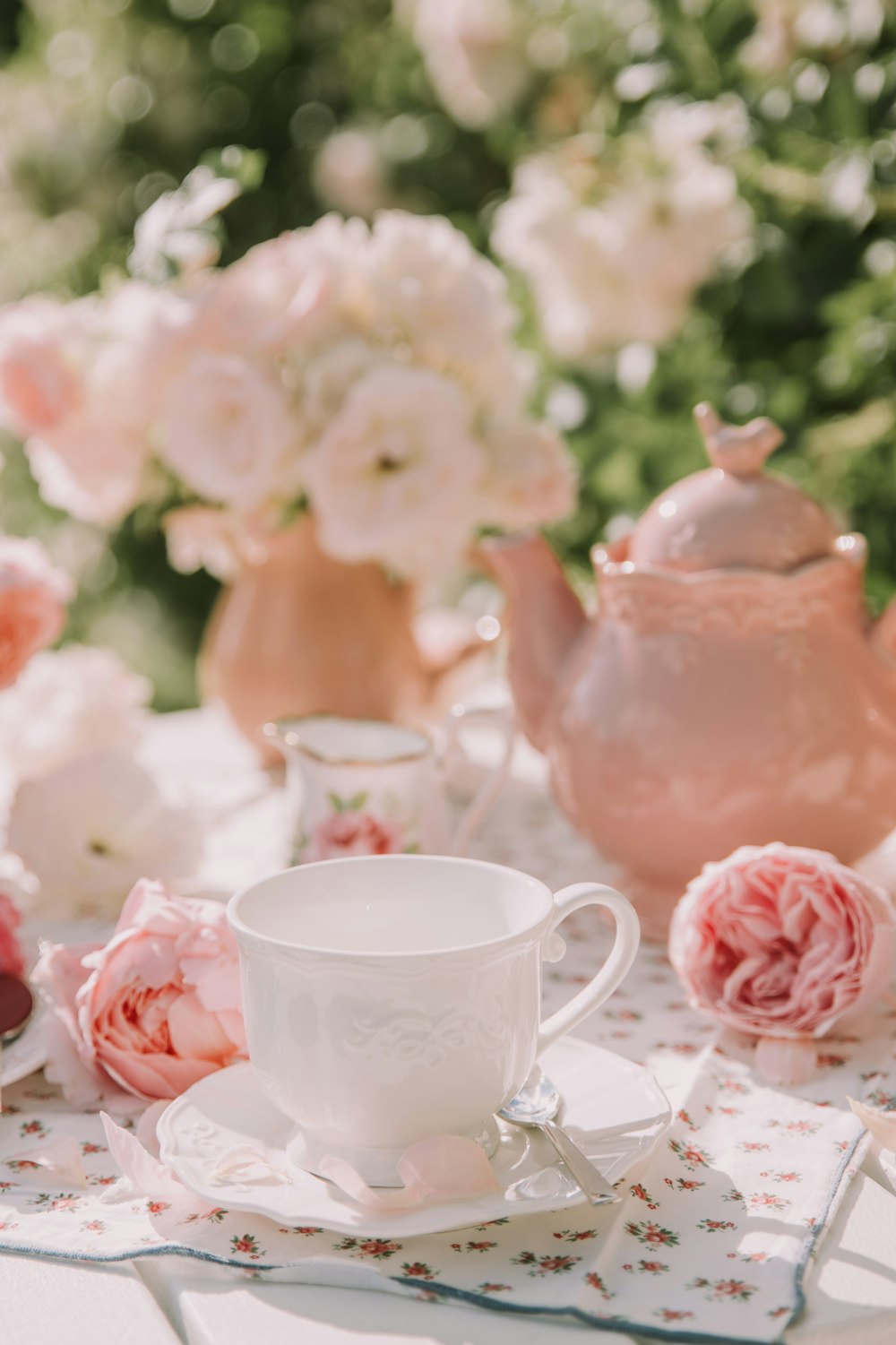 a tea set on a table with pink flowers