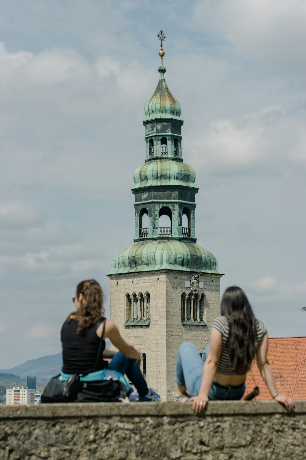 a couple of people sitting on top of a stone wall