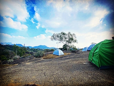 A mobile tent setup on a rocky clearing surrounded by tall pine trees.