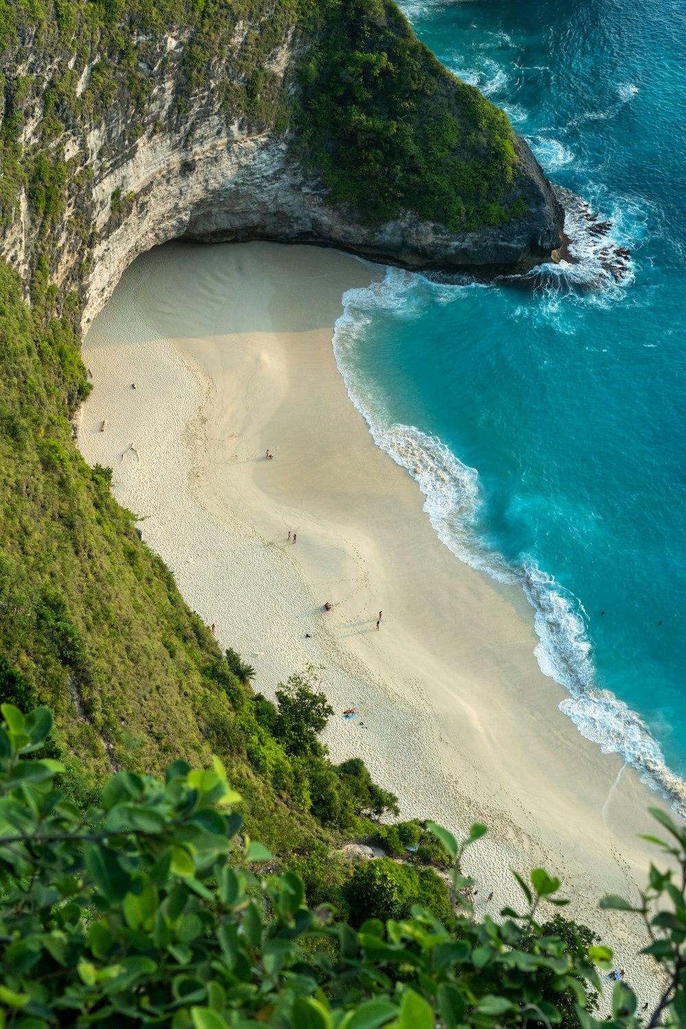an aerial view of a sandy beach with a cliff in the background