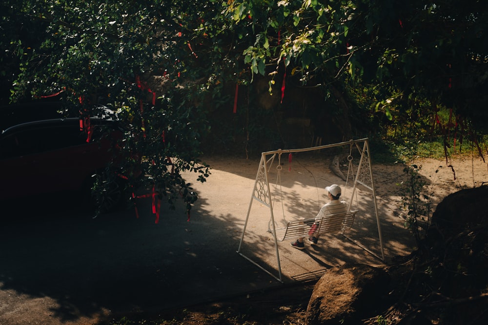 a person sitting on a swing under a tree