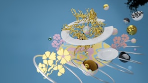 A surreal composition featuring intertwined golden branches, geometric spheres with various textures, and floating white plates. Colorful floral patterns reference delicate organic forms. The background is a pastel blue, providing contrast against the diverse shapes and colors in the scene.