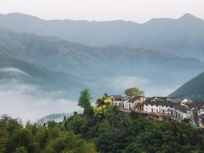 A traditional village home surrounded by lush greenery and misty hills in Karnataka.