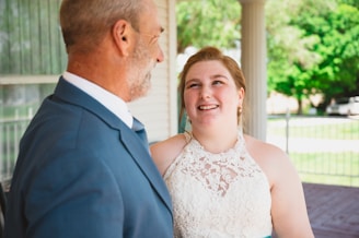 Jason Coomes warmly shaking hands with a happy couple in front of a charming home.